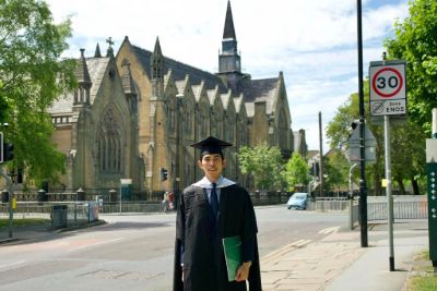 Bunthorn on his graduation day from the School of Law. He is standing in front of church-like building, he is smiling.