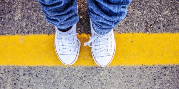 Boy standing on yellow lines at the side of a road