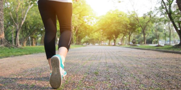 Picture of a person's legs in sport attire walking through a park.