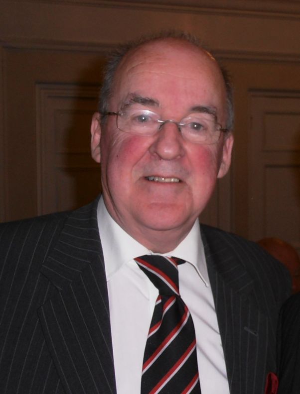 Peter Newham in a suit and tie smiling at the camera