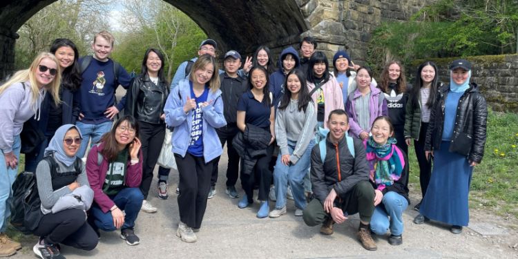 Group of smiling students standing in front of a bridge
