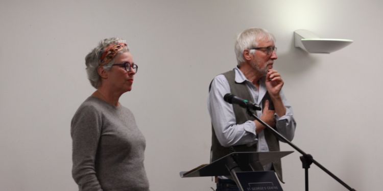 Professor Sara Ryan stands with Professor Luke Clements at a lecturn.