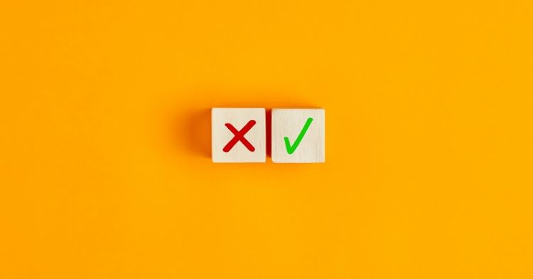 Two wooden blocks, one with red cross, one with green tick, against yellow background