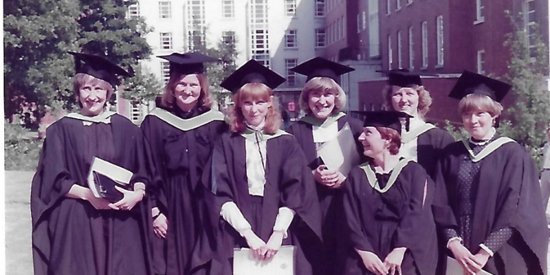 Seven women in graduation gowns and hats