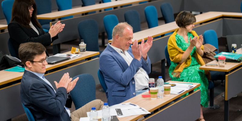 Small audience in lecture theatre clapping