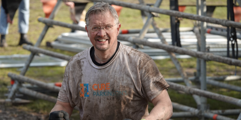 Man covered in mud smiles at camera
