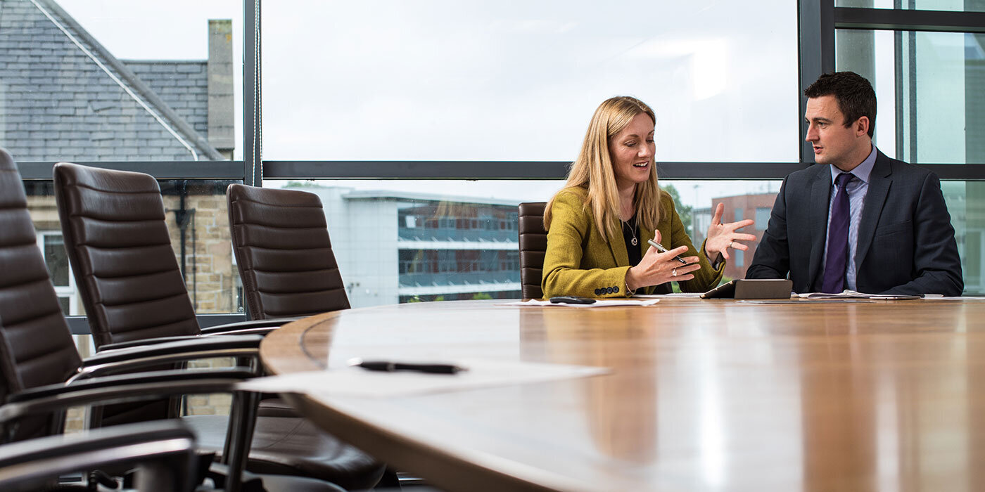 Two academic staff sat together at a table in the School of Law boardroom