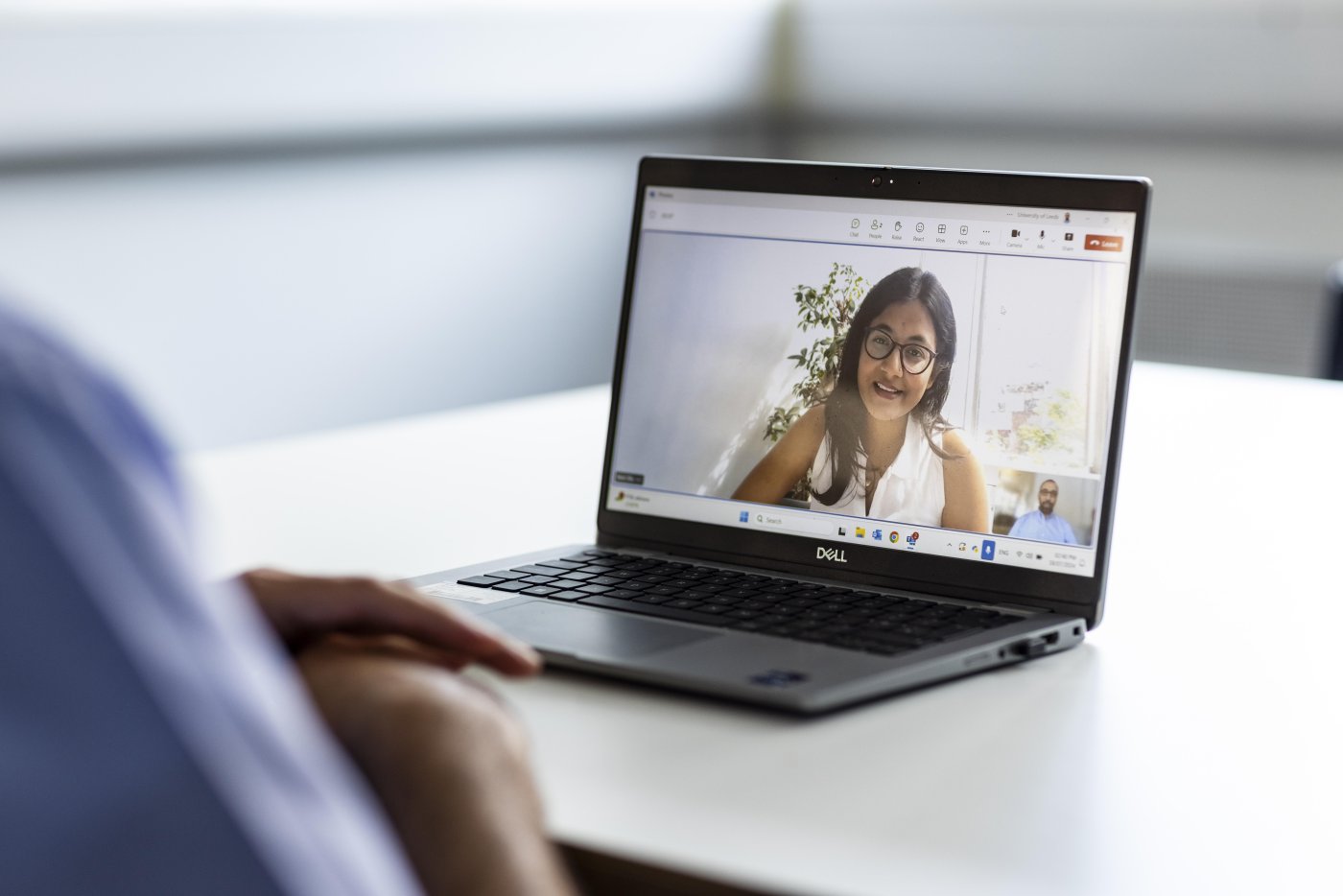 A laptop screen shows a student on a Teams call with their lecturer