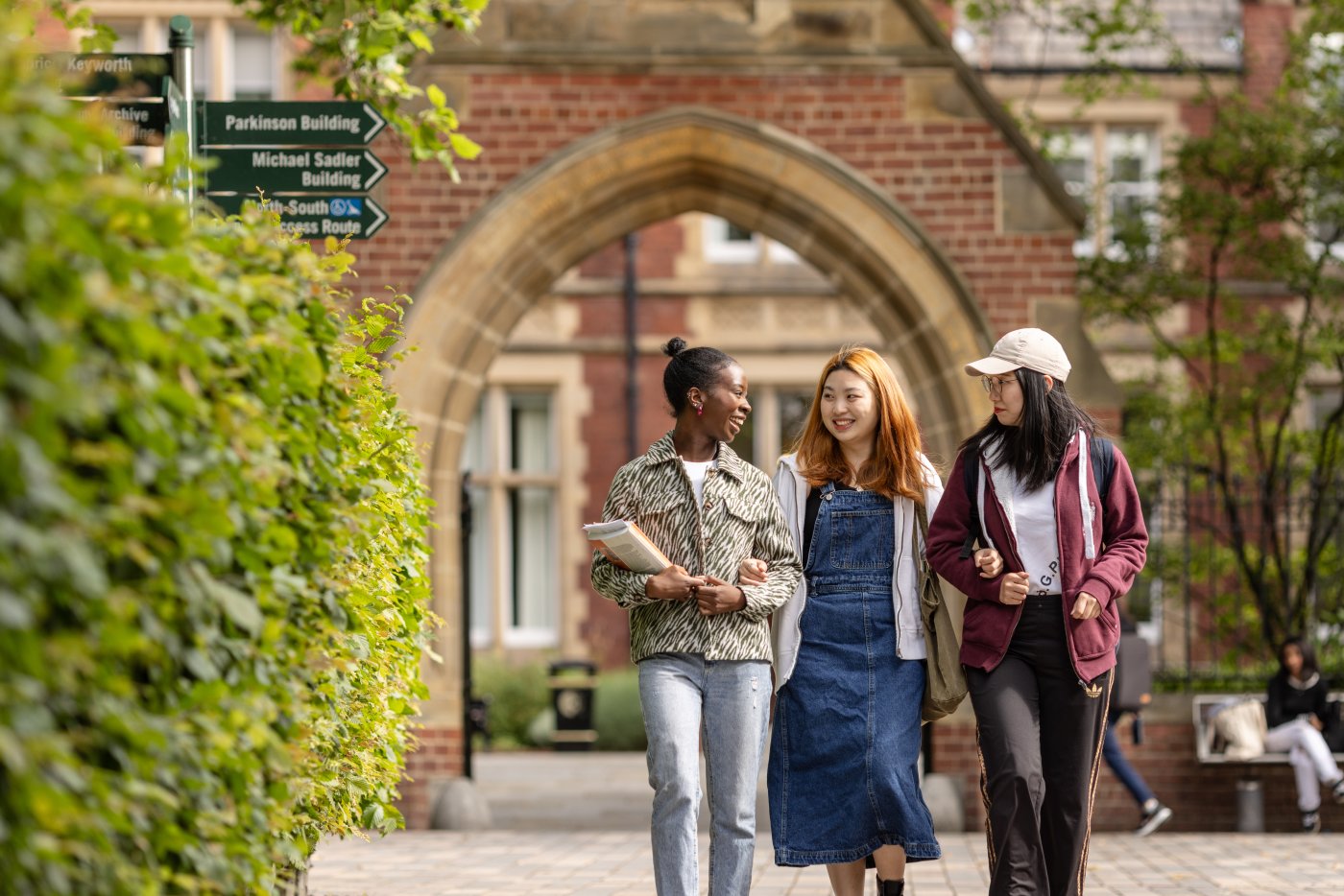 Three postgraduate students walk across the University of Leeds campus.