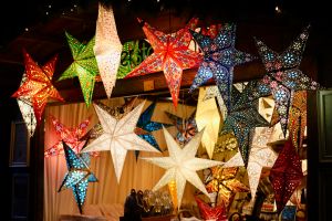 Brighly coloured star shaped lanterns hanging from a wooden market stall.