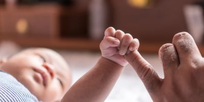 A baby holding an adult's finger