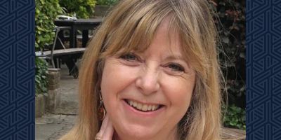 Smiling photo of Prof Joanne Conaghan against a navy blue background