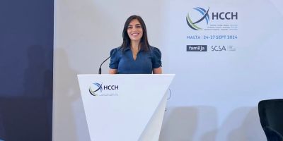 Dr. Nazia Yaqub standing at a podium branded with the HCCH (Hague Conference on Private International Law) logo.