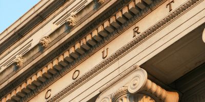 the exterior of a courthouse building, featuring classical architectural elements like stone columns and the word 