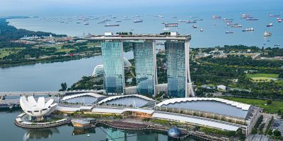 An aerial shot of the bay in Singapore, featuring glass buildings, green areas and boats.