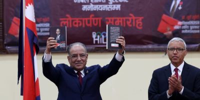 尼泊尔总理高举着苏贝迪教授的传记。苏贝迪教授在他身后鼓掌。