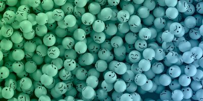 A ballpit-style collection of 3D emoji balls in blue and green with a variety of happy, sad and other expressions, based on keyboard emojis.