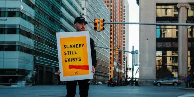 Man holding a sign reading 'Slavery still exists'