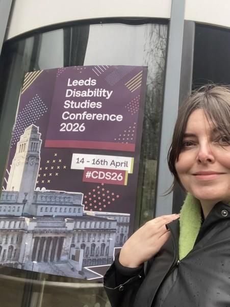 Image of our colleague Mindy standing next to the conference poster