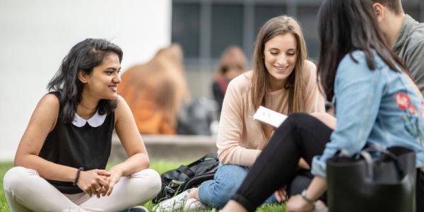 Students chatting, sitting on the lawn at University of Leeds