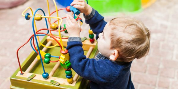 Nursery age child playing with an educational toy outdoors