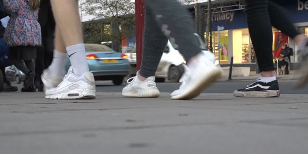 Photograph of people walking down a street (feet only)