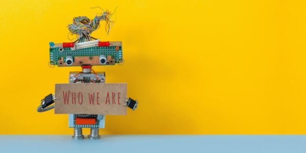 Small robot holding a sign that reads 'Who we are'