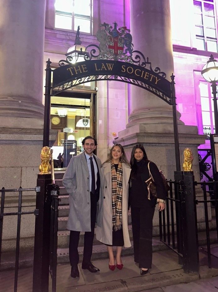 Three people standing outside the Law Society building smiling at the camera