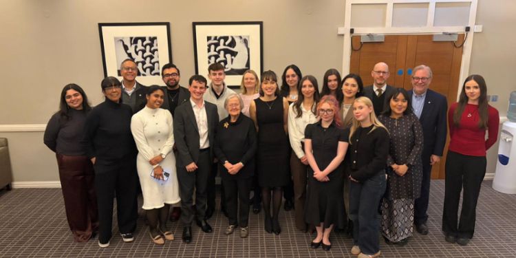 All the dinner attendees standing together and smiling at the camera