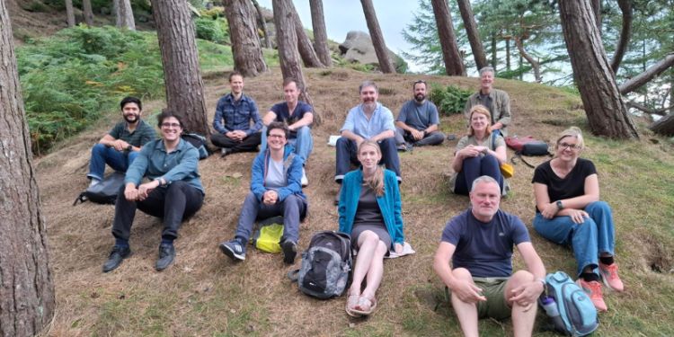A group picture of the participants sitting in the woods and smiling. 