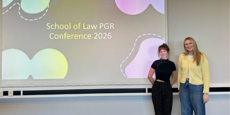 Organisers Sophie and Hannah against the background of 'School of Law PGR Conference 2026'