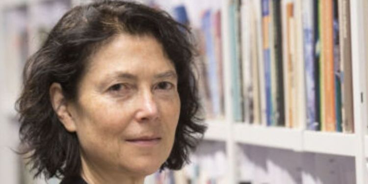 Photograph of Prof Walby standing next to bookshelves