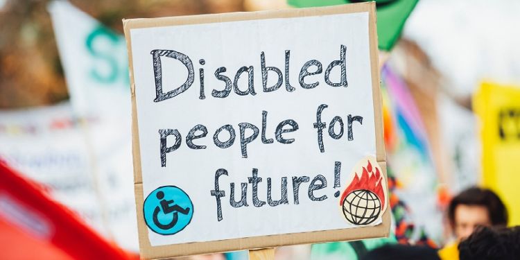 Placard held up against blurred protest background, with the words &quot;Disabled people for future&quot; handwritten.