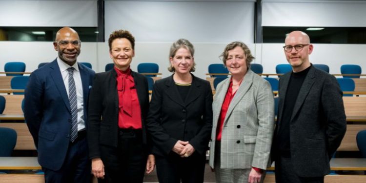 The speakers standing next to  each other in the Moot Court Room. 