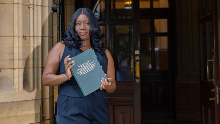 A smiling photo of Oluwabunmi Adaramola outside the Great Hall, holding her bound thesis.