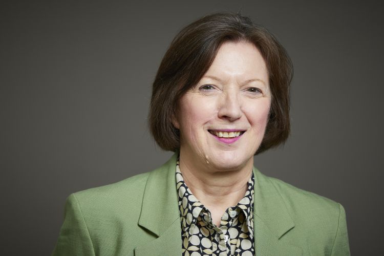Image of a woman with brown hair in a pale green blazer