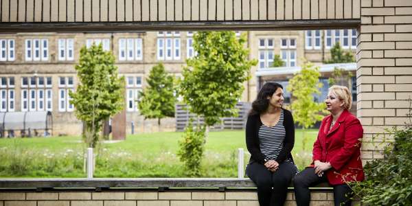 Students sat on a wall outside on campus talking