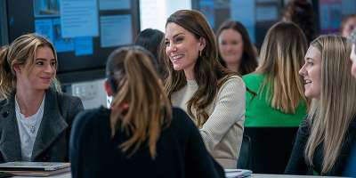 Princess of Wales chats with a small group of university students in a workshop setting.