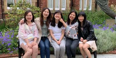 5 MA students who completed the Student into Schools Go Global Scheme sat on a bench on campus