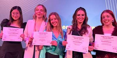 Five women smile at the camera holding certificates