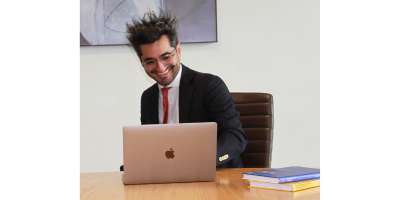 Man at a desk smiles at an open laptop