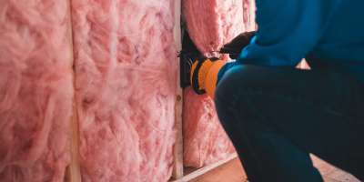 A person installing insulation in a home.