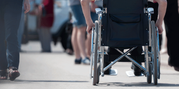 Someone using a wheelchair on the street, viewed from behind